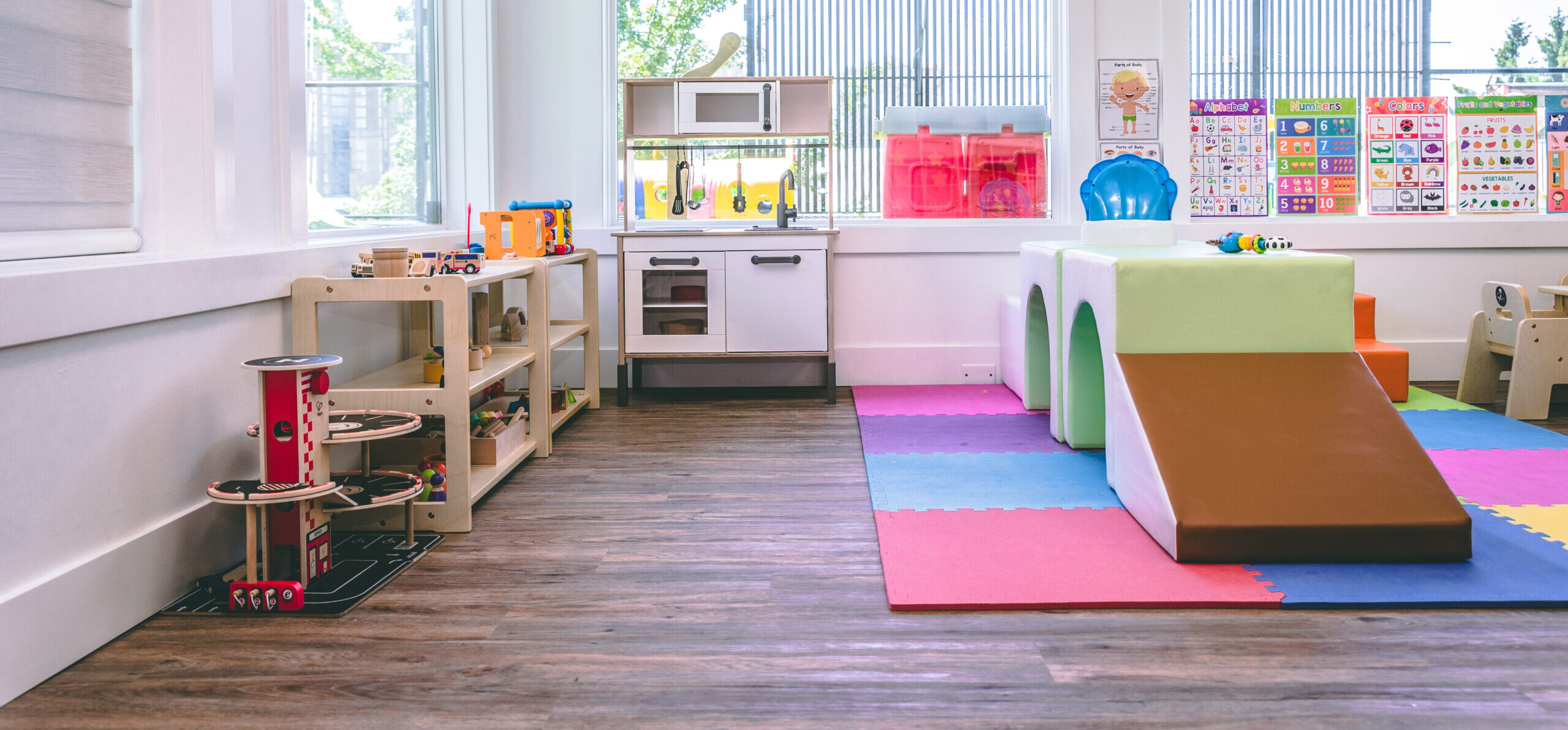 A bright Starlight playroom with a soft climbing slide, play kitchen and reading corner